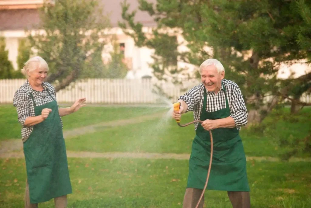 Guide on Elderly couple with garden hose smiling  