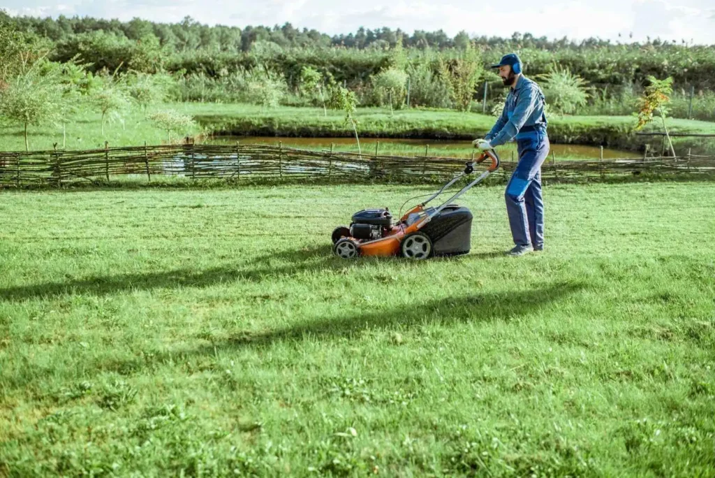 Showing Gardener cutting grass with lawn mower  