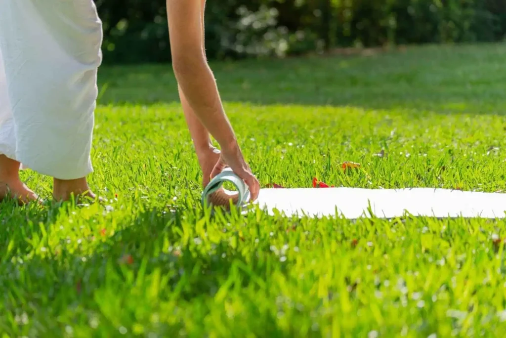 Describing Young woman rolling yoga mat in a green park  