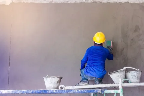 Worker plastering wall during construction
