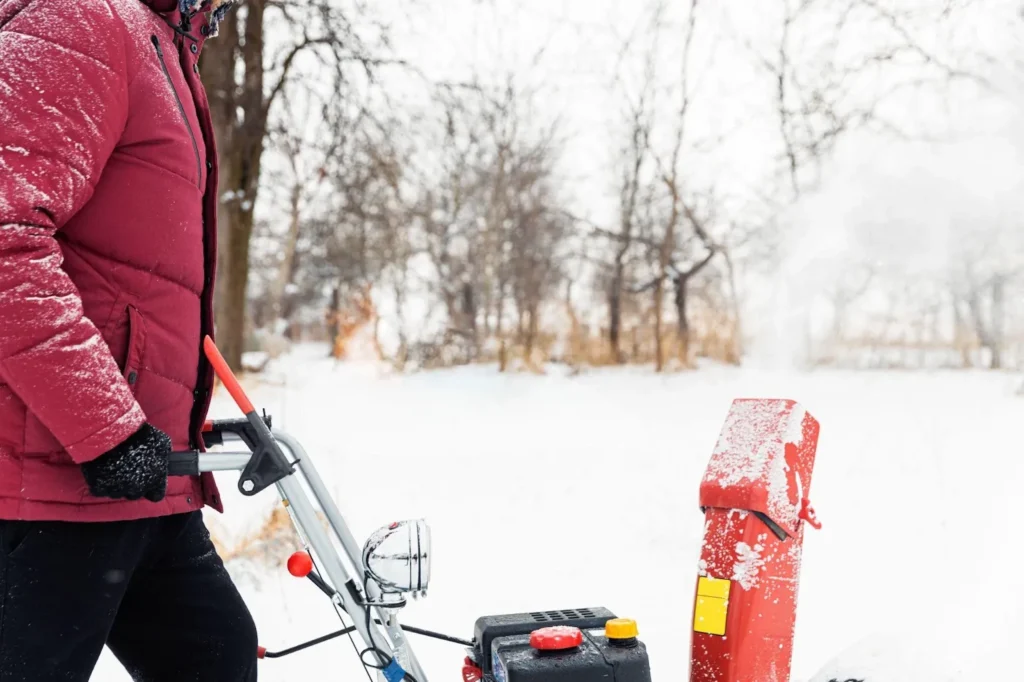 Man using a red snowblower machine outdoors to remove snow